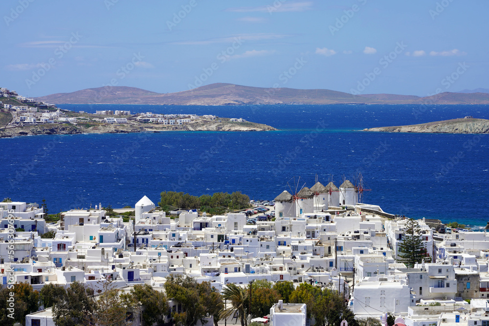 Picturesque view of Mykonos Island with whitewashed houses and windmills against blue Mediterranean sea, Greece
