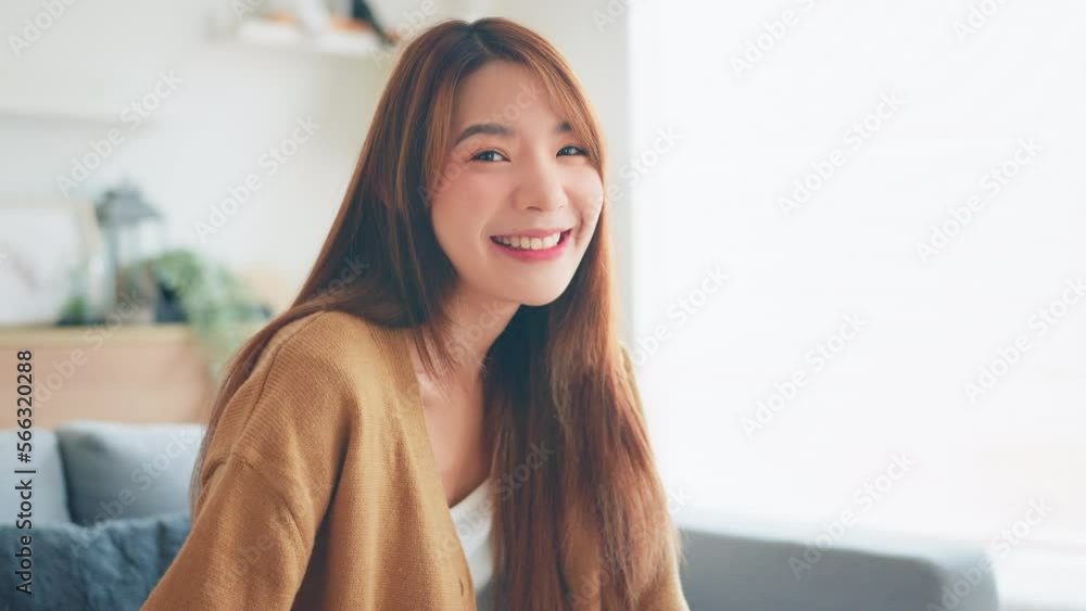 Confident smiling young adult asian woman looking at camera while sitting at home, Happy beautiful lady pretty face dental smile posing alone indoors, Slow motion close up view portrait Confident smiling young adult asian woman looking at camera while sitting at home, Happy beautiful lady pretty face dental smile posing alone indoors, Slow motion close up view portrait