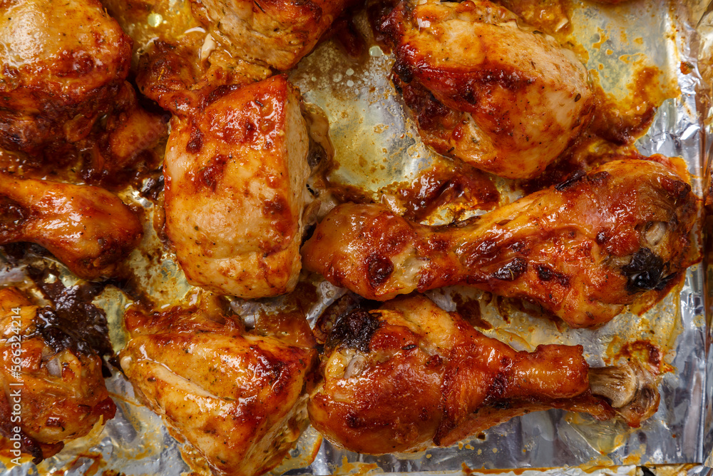 Baked chicken legs and breasts in sauce and herbs on foil close-up. Baked chicken legs and breasts in sauce and herbs on foil close-up.