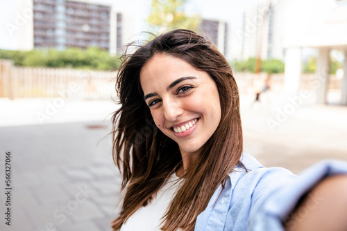 Selfie-portrait of pretty girl in the city. Portarit of happy young beautiful woman doing a selfie photo on the camera. 