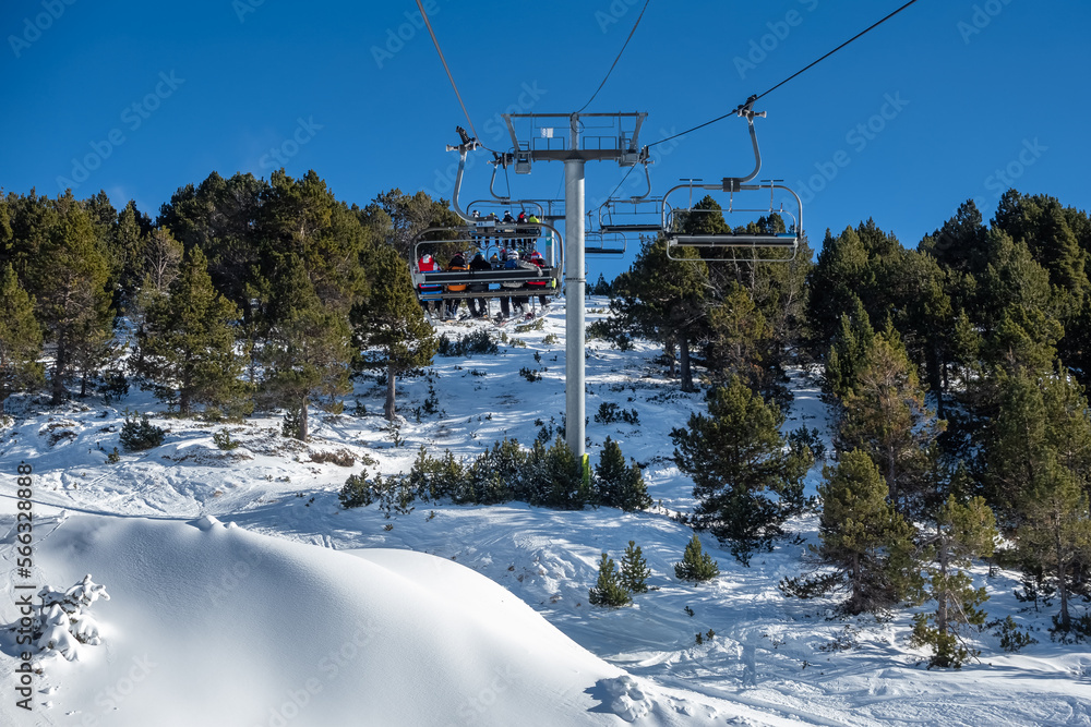 Ski resort lifts with skiers sitting on chairs to climb high in the mountains, Andorra. Ski resort lifts with skiers sitting on chairs to climb high in the mountains, Andorra.