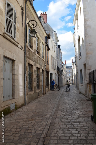 Cobbled street lined with old houses in an old part of town  there are only 2 cyclists on the street  perspective view.