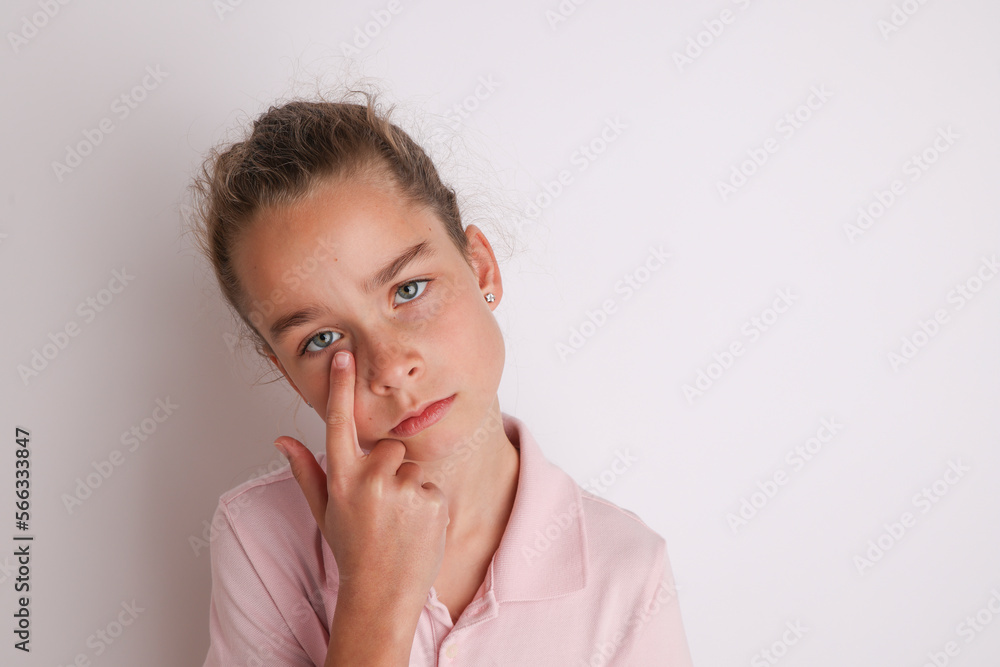 Little emotional teen girl in pink shirt 11, 12 years old on an isolated white background. Children's studio portrait. Place text, to copy space for inscription, advertising children's goods.