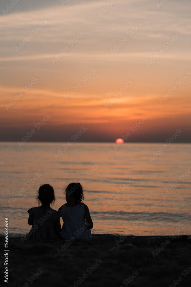 Two European girls enjoy the sunset on the sea, play, hug, smile. Love sisters on the beach. as a gift from daughters mother's day. Family vacation at the hotel. Happy childhood in summer. High