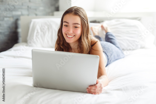 teen with laptop on bed