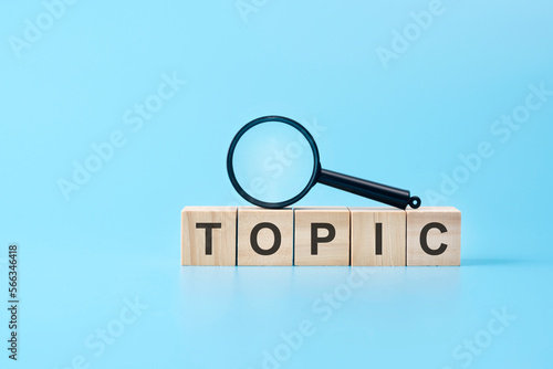 wooden blocks with the text: topic with magnifying glass. business concept