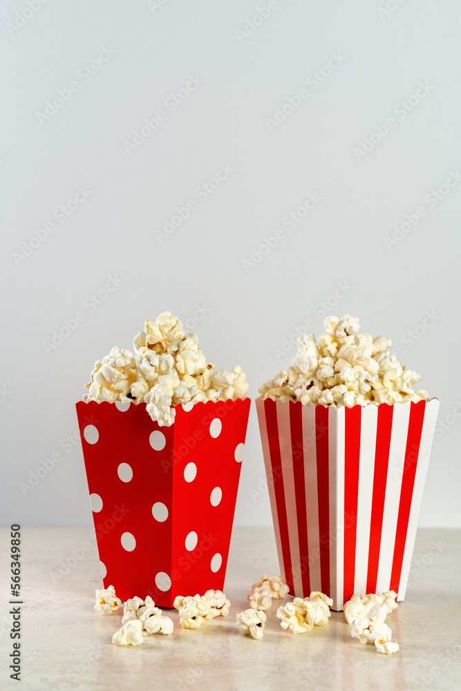 two bags of popcorn in red and white on a light background, front view, copy space