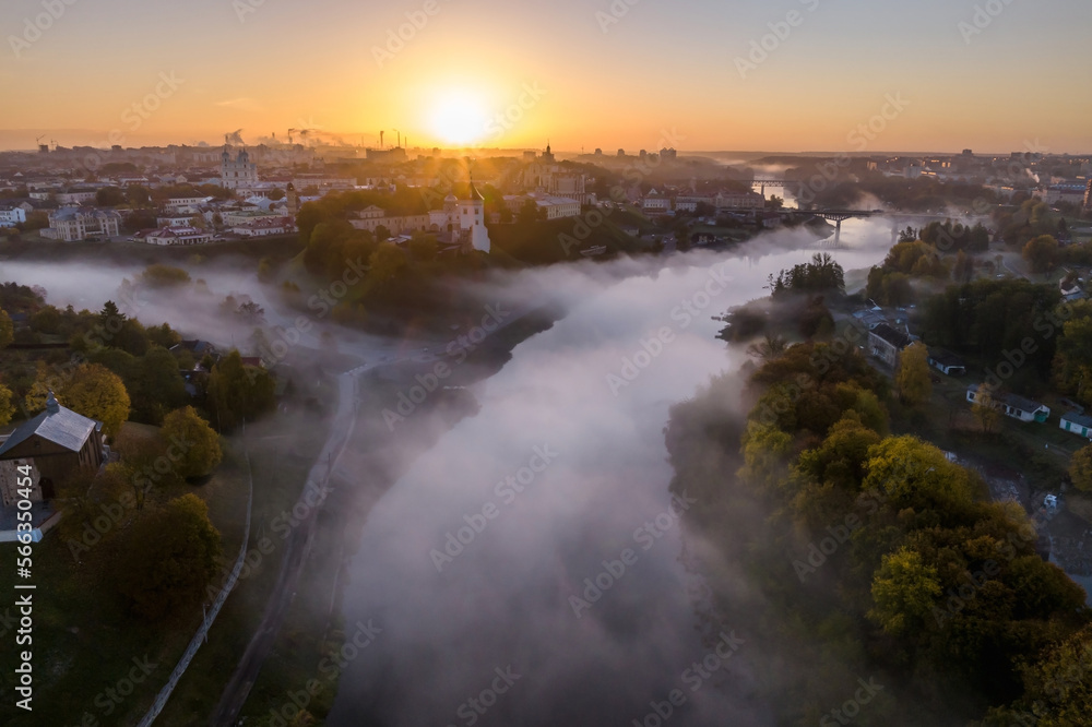 earlier foggy morning and aerial panoramic view on medieval castle and promenade overlooking the old city and historic buildings near wide river with bridge