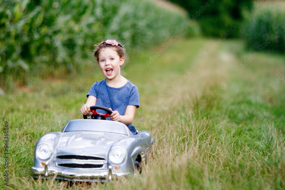 Little preschool kid girl driving big toy car and having fun with driving in nature Little preschool kid girl driving big toy car and having fun with driving in nature