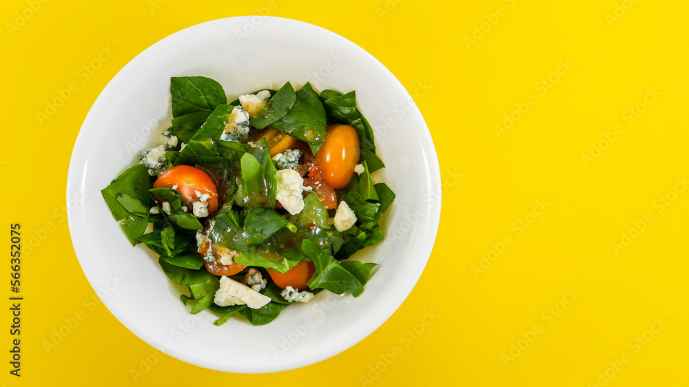 Salad from baby spinach leaves with tomatoes and blue cheese and dressing