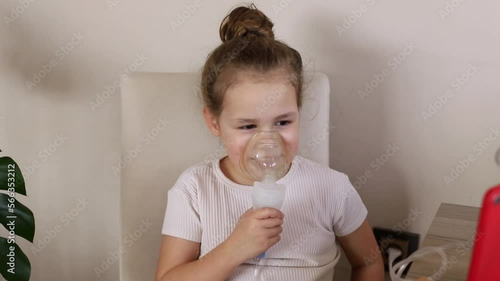 a little girl is doing an inhalation. Treatment of asthma, cough. the child does the inhalation procedure with a nebulizer of the respiratory tract. treating a child for cough. compression inhaler. 