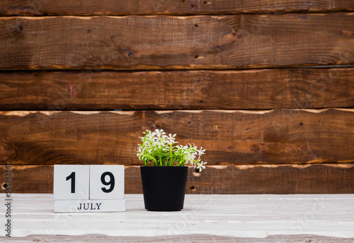 July calendar with number  19. Planner copy space on a wooden brown background. March number icon. Place for text background calendar photo