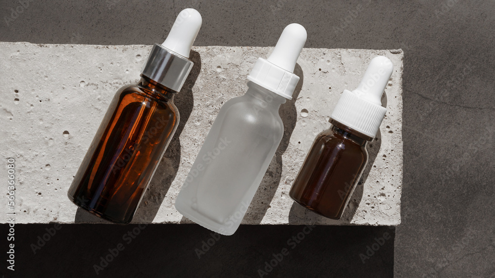 cosmetics bottle from dark amber glass and white frosted glass on concrete background. Hard shadow, bright sun. Mock Up for Cosmetics, minimalism, go for face and body, oil pipette cosmetics bottle from dark amber glass and white frosted glass on concrete background. Hard shadow, bright sun. Mock Up for Cosmetics, minimalism, go for face and body, oil pipette