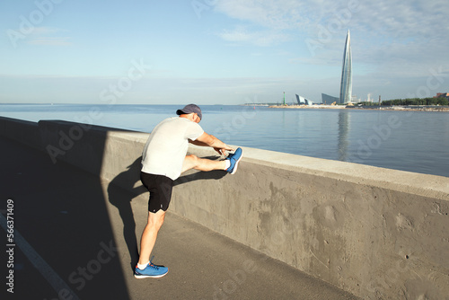 Fototapeta Naklejka Na Ścianę i Meble -  Athlete warming up on the embankment opposite the tower
