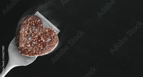 Obraz na płótnie heart shaped beef burger patty on a grilled spatula. dark background place for text. valentines day celebration concept w salonie