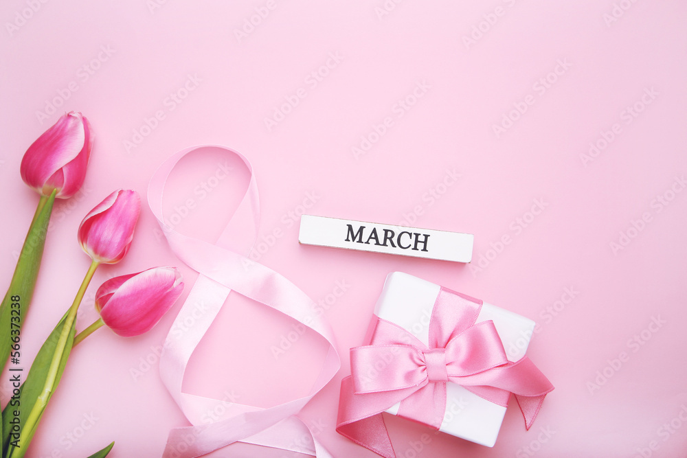 Ribbon in shape of figure number 8, gift and tulips flowers on pink background