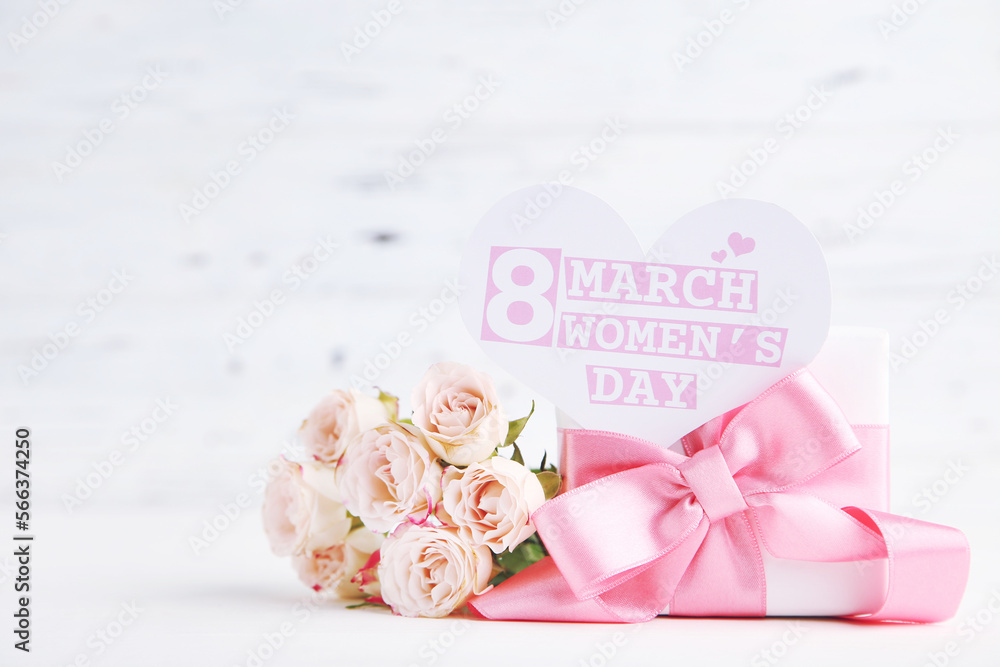 Bouquet of roses, gift and card in shape of heart with text 8 March Women's Day on white wooden background Bouquet of roses, gift and card in shape of heart with text 8 March Women's Day on white wooden background