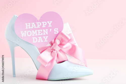 Gift box, card in shape of heart with text Happy Women's Day and blue high-heeled shoe on pink background