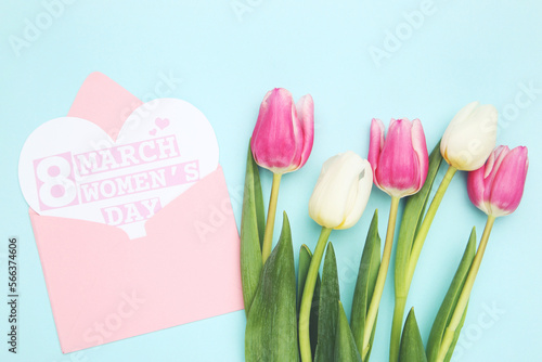 Flowers of tulips and envelope with card in shape of heart with text 8 March Women's Day on blue background