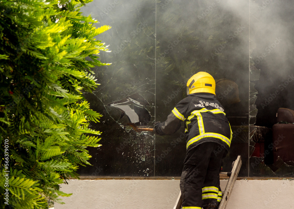 Fototapeta premium National Fire Fighter of Sri Lanka trying to fight a fire going on in a commercial store in Colombo. They are trying to enter the building by breaking glass windows.