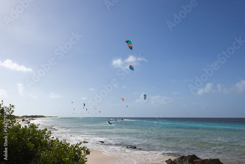 Sandy beach with turquoise water and kitesurfers on the horizon. Kitesurfing lessons.