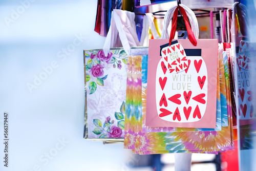 Colourful Valentine's day gift paper hand bags with love and red hearts hanging on front of shop. Design element and holiday present shopping bag background. photo