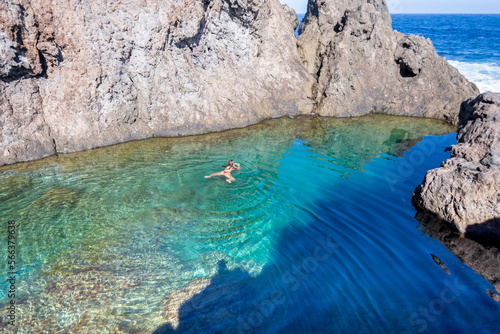Young woman in bikini swimming in the water of a natural pool of volcanic rock in Tenerife