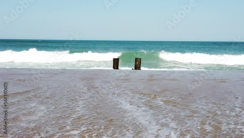 Waves Crashing Against a Old Torn Down Dock On The Sand photo