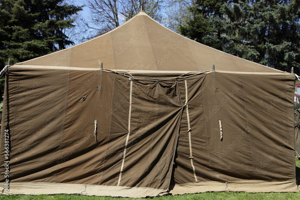 Big military tent khaki Tarpaulin on trees and blue sky background ...