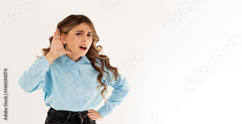 Portrait of a young girl with hand on ear. What did you say? Isolated on white background