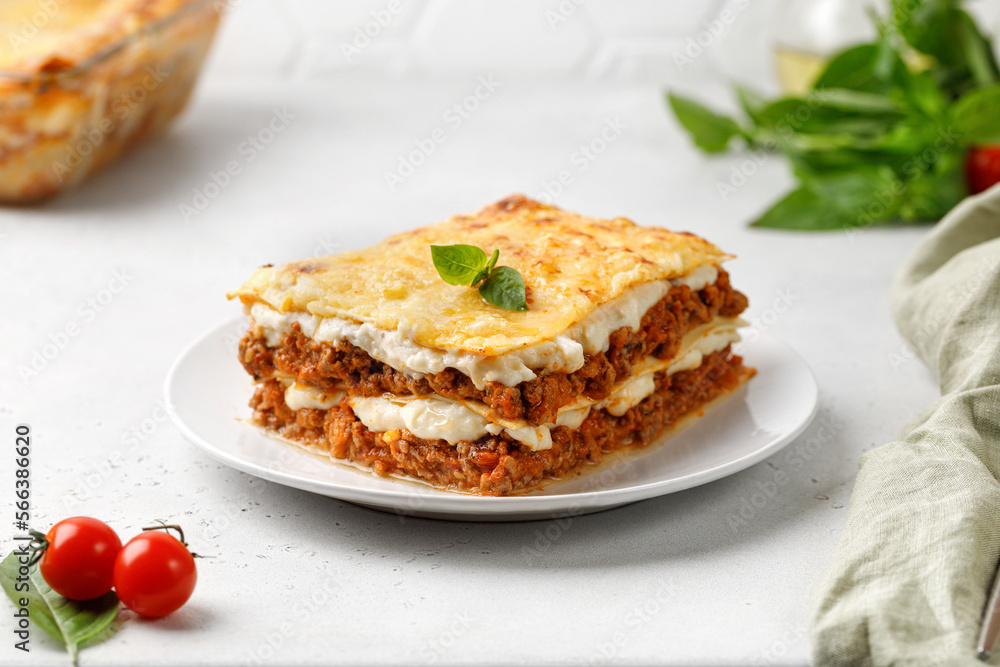 Piece of baked italian lasagna with bolognese meat sauce on grey background.