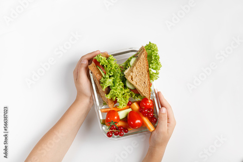 Small kid's meal, take away school food. School lunch in box, container. Toasts, sandwiches, vegetable snack. Kid's hands.