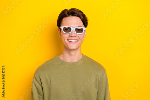 Photo of optimistic cheerful man wear khaki clothes watching interesting film isolated on yellow color background
