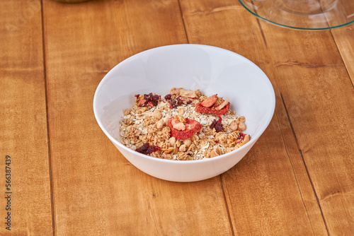 Oatmeal muesli in white plate on the wooden table.