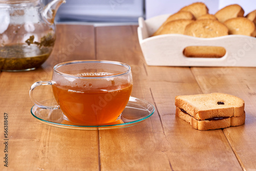 Tea in a glass cup on the wooden table and toast with plum jam.