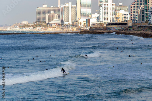 Surfers in distance in Tel Aviv and hotels or residential buildings next  to coastline in Tel Aviv . A little shadow of cloud on foreground