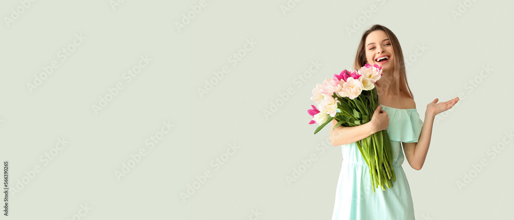 Happy young woman with bouquet of beautiful tulips on light background with space for text