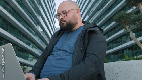 Wallpaper Mural Plus size man in glasses with laptop outside with office buildings on background close his device and finishing work. Male manager or banker using computer outdoors Torontodigital.ca