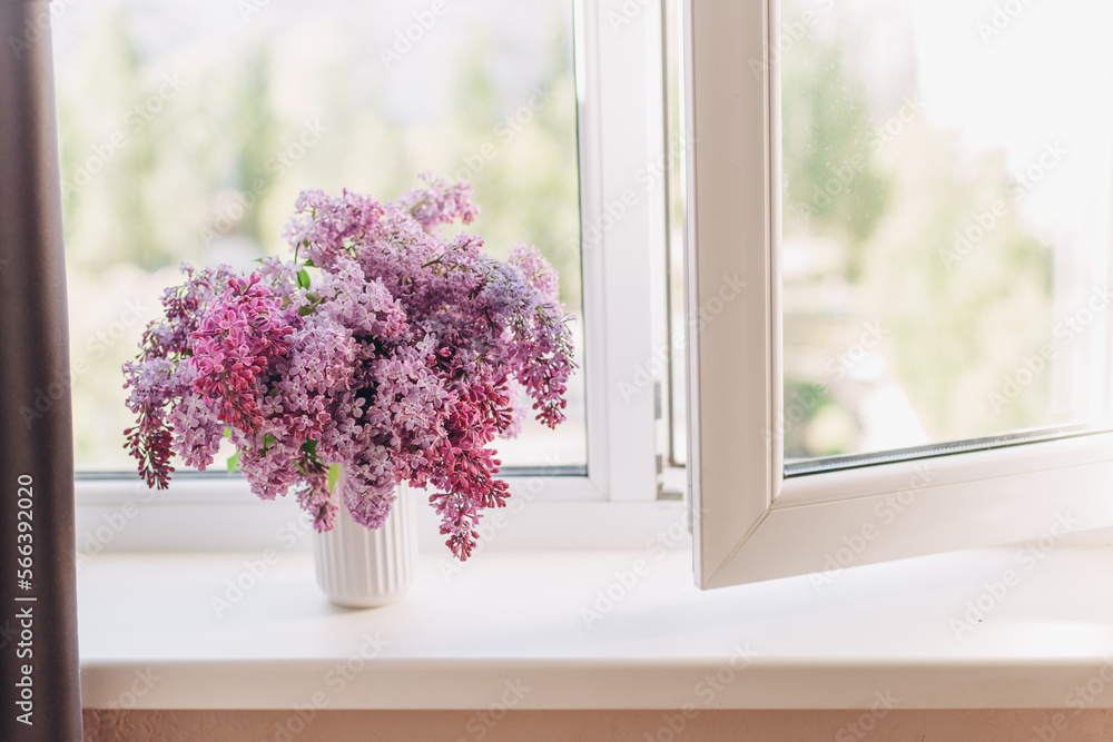 Vase with a bouquet of spring lilac flowers on the windowsill Vase with a bouquet of spring lilac flowers on the windowsill