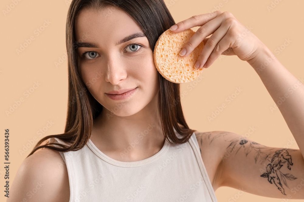Young woman with makeup sponge on beige background, closeup Young woman with makeup sponge on beige background, closeup