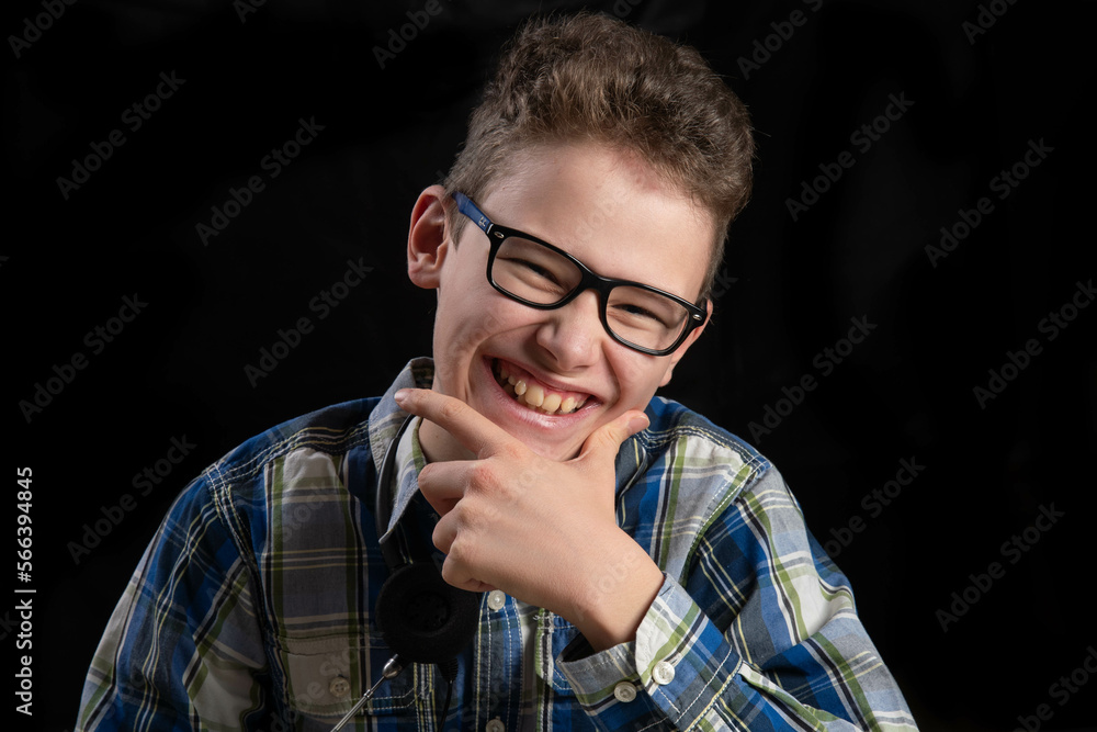 Child with glasses and curls laughing into camera against dark background Child with glasses and curls laughing into camera against dark background