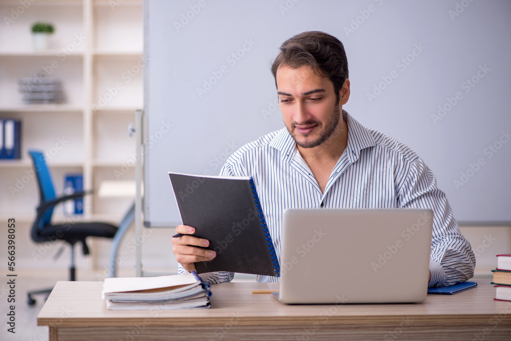 Young male teacher sitting in the classroom Young male teacher sitting in the classroom