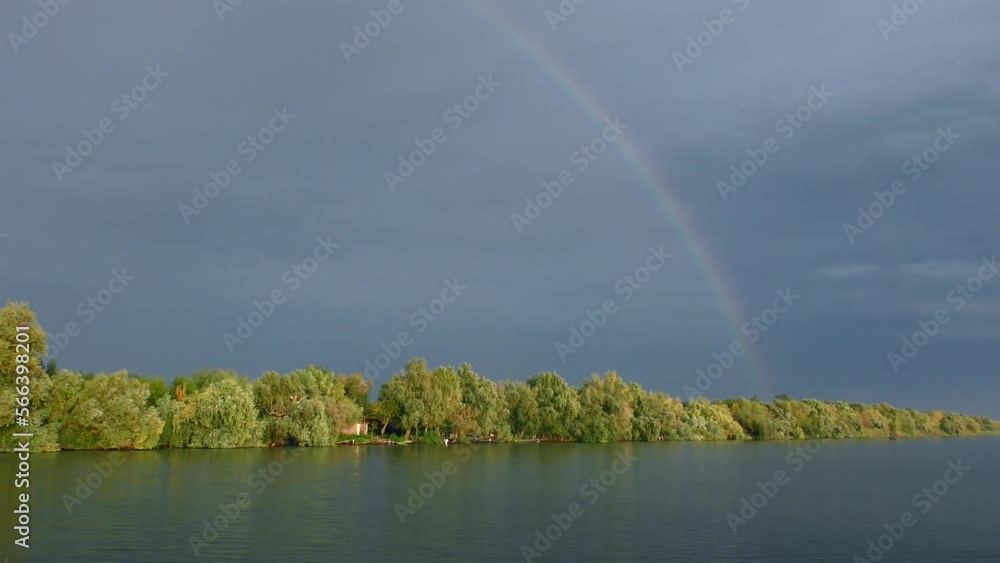 In the sky above the river, the rainbow gradually fades and loses color saturation. In the sky above the river, the rainbow gradually fades and loses color saturation.