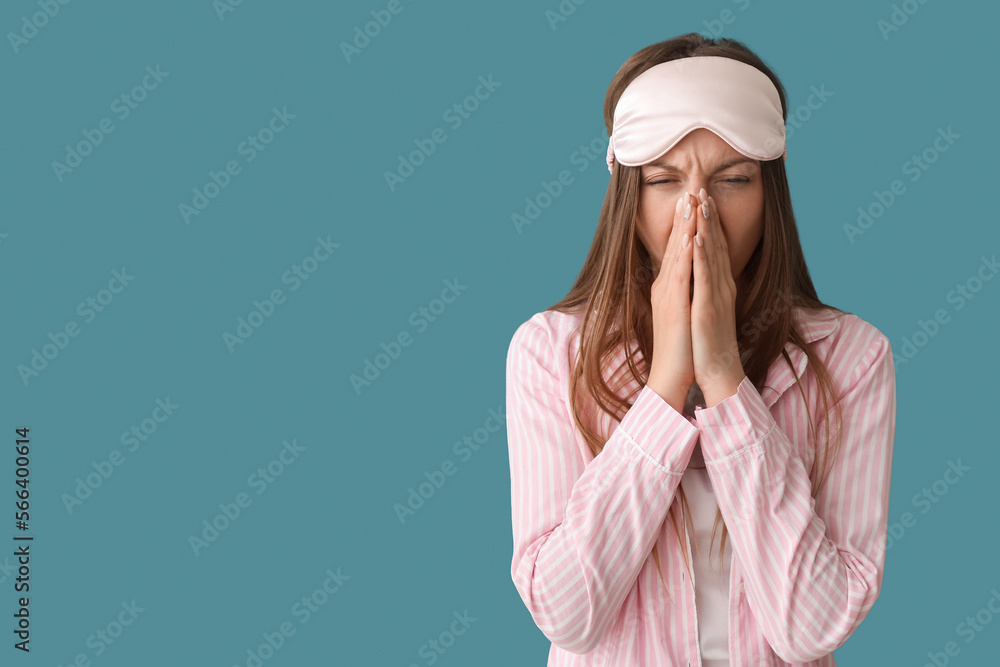 Young woman with sleeping mask yawning on blue background Young woman with sleeping mask yawning on blue background