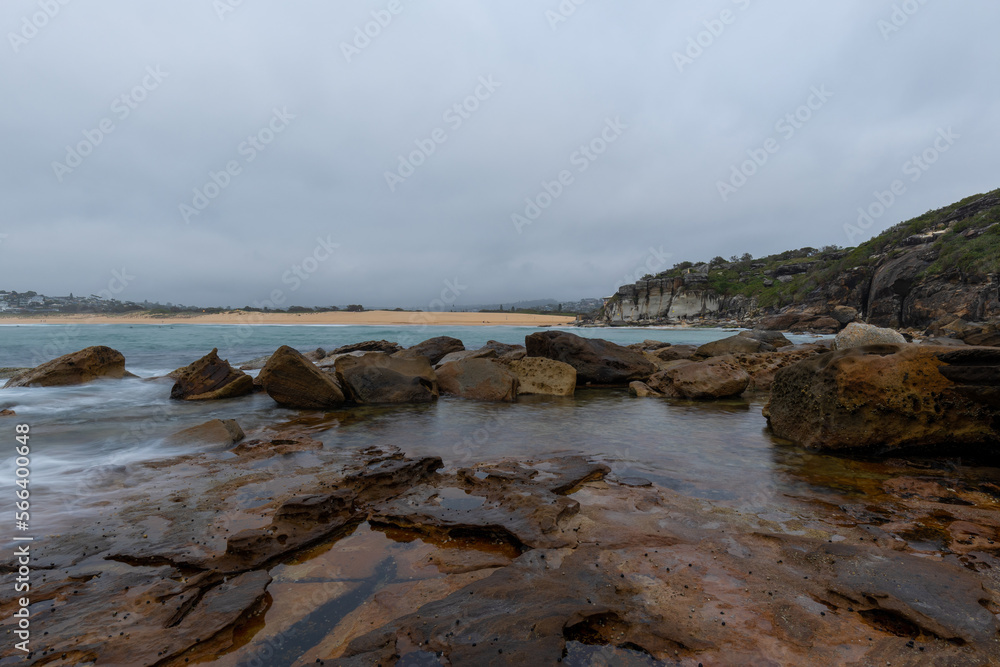 Rocky coastline of North Curl Curl with overcast sky.