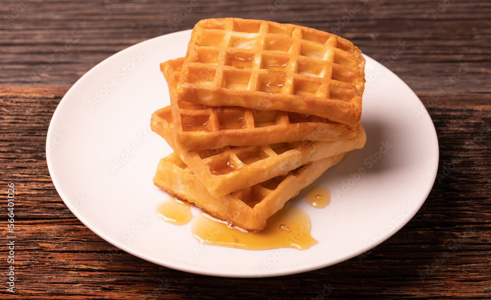 Delicious Belgian waffles with honey served on white plate and wooden background, rustic concept. Delicious Belgian waffles with honey served on white plate and wooden background, rustic concept.