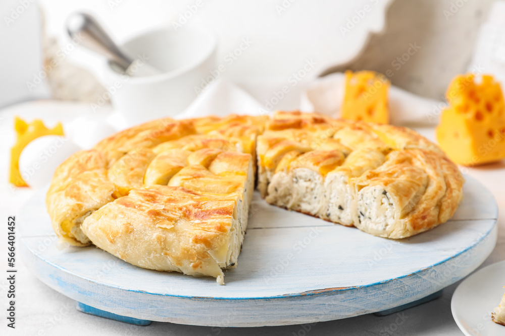 Board with pieces of delicious cheese pie on white table Board with pieces of delicious cheese pie on white table