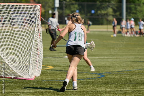 THE WOODLANDS, TEXAS - OCTOBER 2022: The Woodlands High School varsity lacrosse team is playing in a  tournament at  Alden Bridge Sports Park. The teenage girls are wearing white and green uniforms