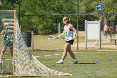 THE WOODLANDS, TEXAS - OCTOBER 2022: The Woodlands High School varsity lacrosse team is playing in a  tournament at  Alden Bridge Sports Park. The teenage girls are wearing white and green uniforms