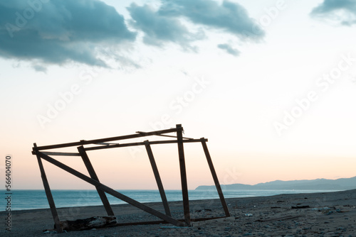 sunset over the sea with a wooden construction on the beach  © Karim